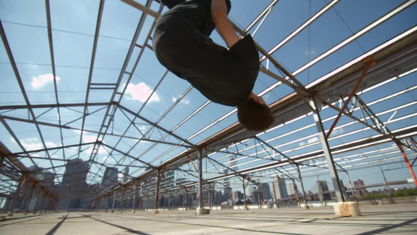 A man does a back flip outside in a building under construction
