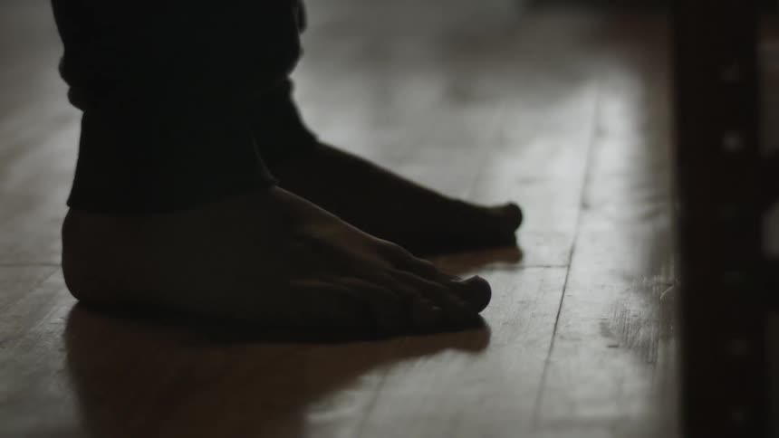 Two bare feet step together on a wooden floor