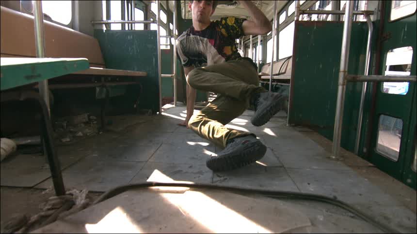 A man break dancing in an empty commuter train car