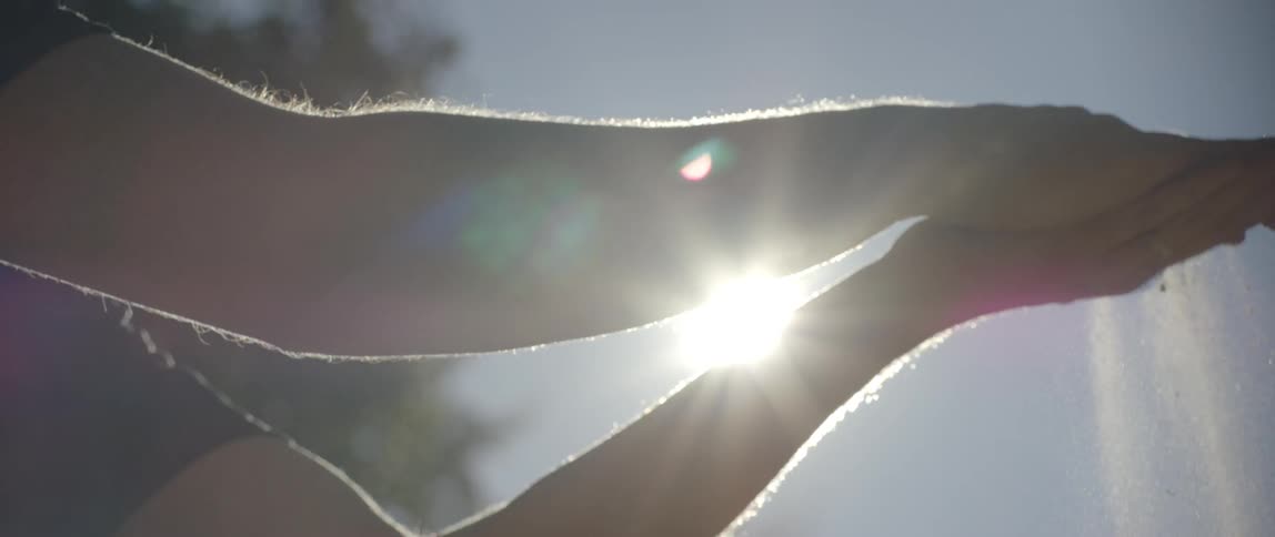 Two hands crumple dirt between them in the sunlight