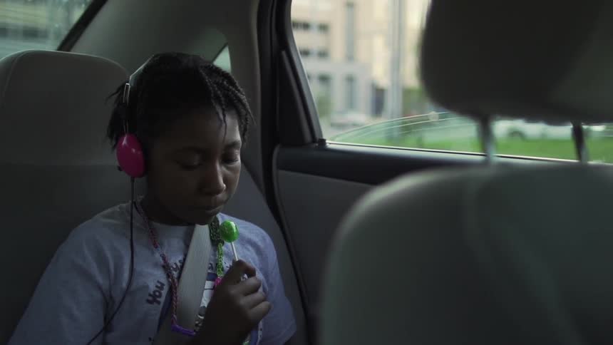 The child sits with the lollipop in the car