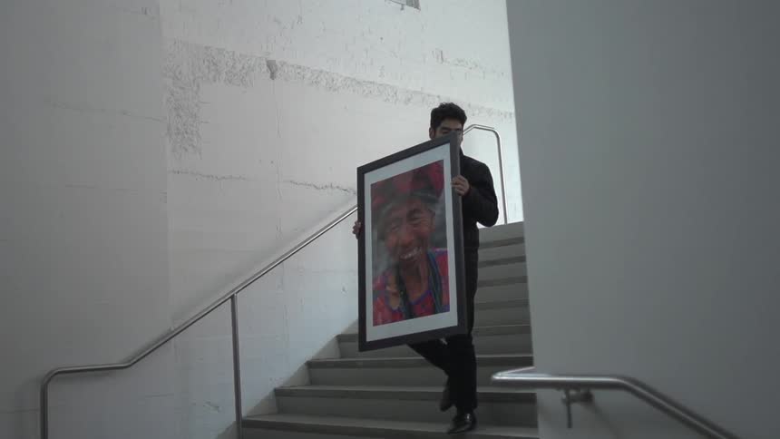 Man carrying a painting goes down the stairs