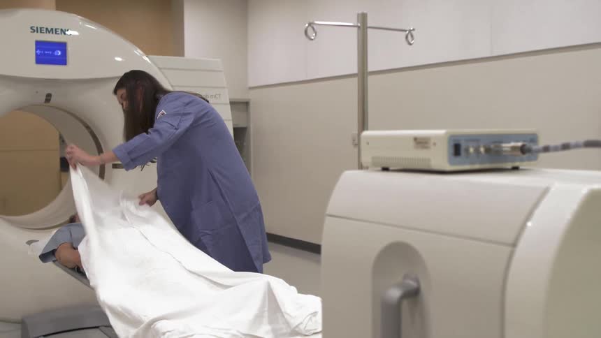 A woman puts a sheet over a man before operating a machine