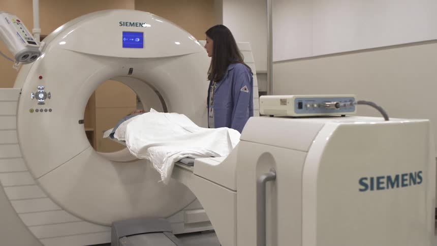 A woman stands near an ct machine