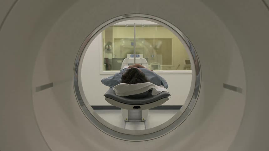 Person laying on a platform slowly entering an x-ray machine