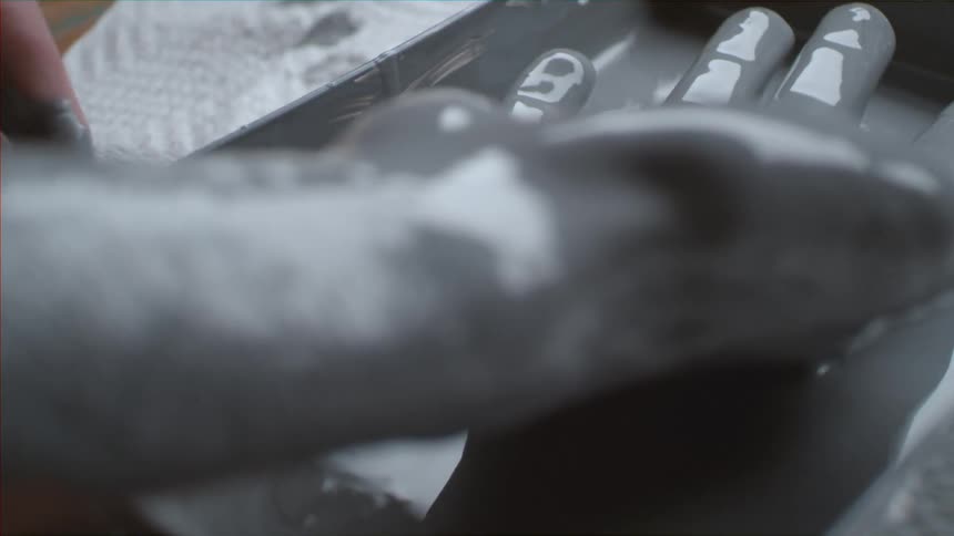 Person lifting their paint covered hand from a container of grey paint