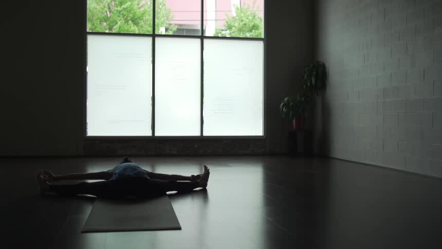 Girl doing yoga in front of a window in a dark room