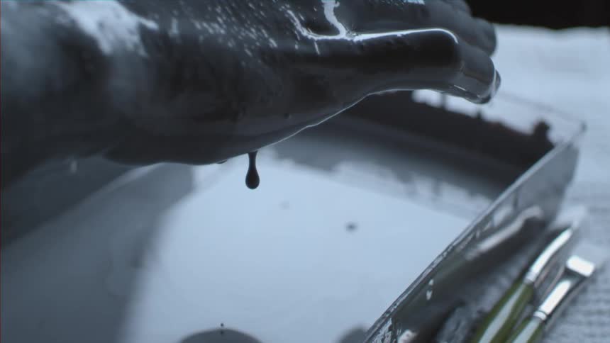Paint dripping from a persons hand that is covered in paint