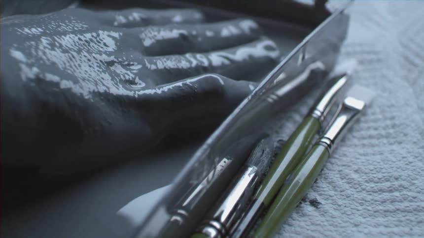 A person places their hand in grey paint