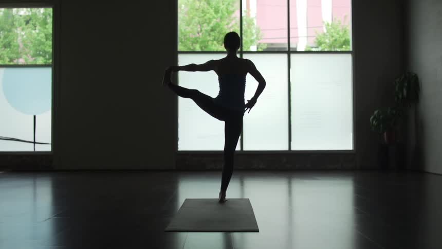 Woman doing yoga stretches in a dark room