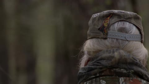 A man with a bushy white beard exhales smoke