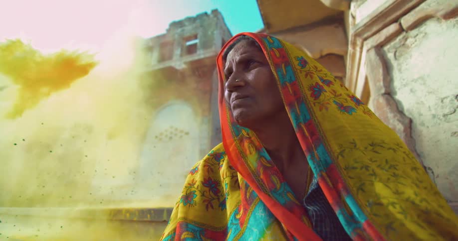 Older woman sits motionless while dirt flies through the air near her