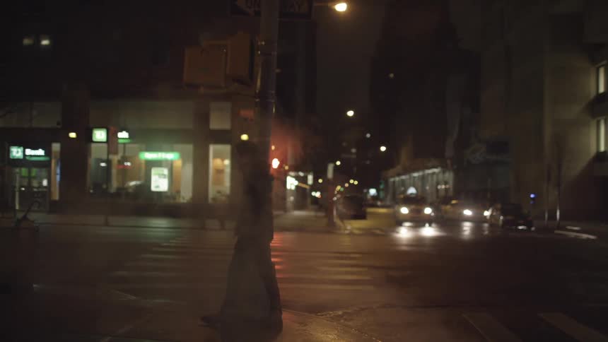 Man walks on the pavement in the dark street at night