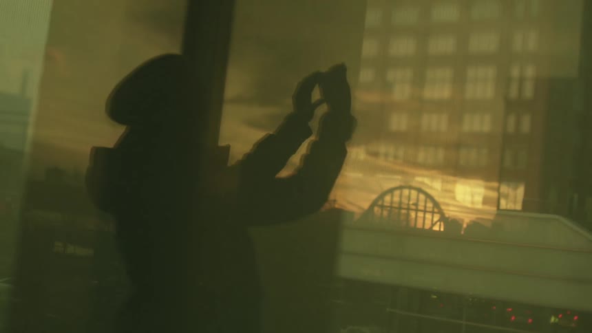A woman records video of a city as she goes up an elevator