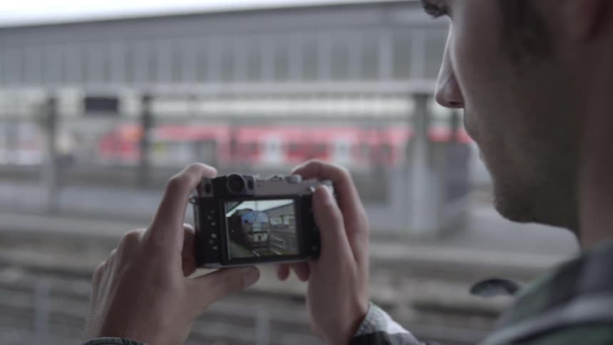 Man takes a photo of a train on his digital camera