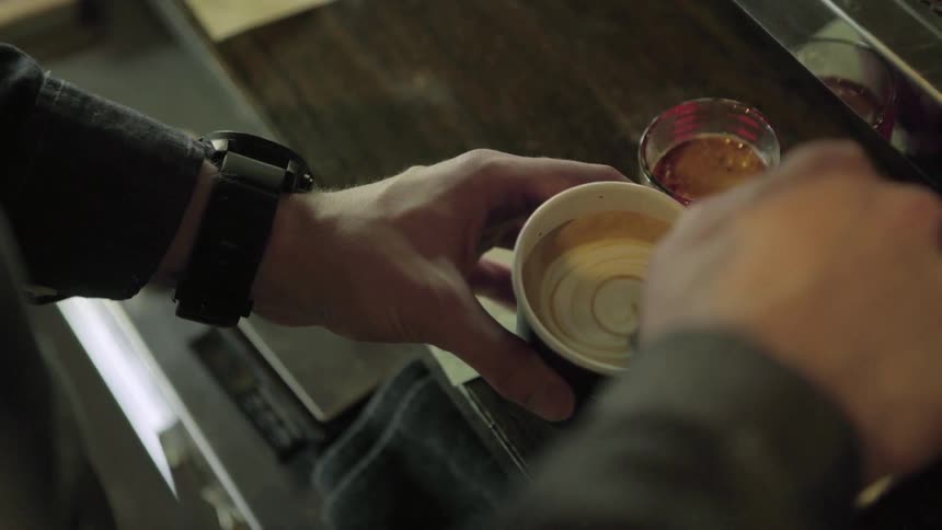 A man pouring steamed milk into a cup of coffee