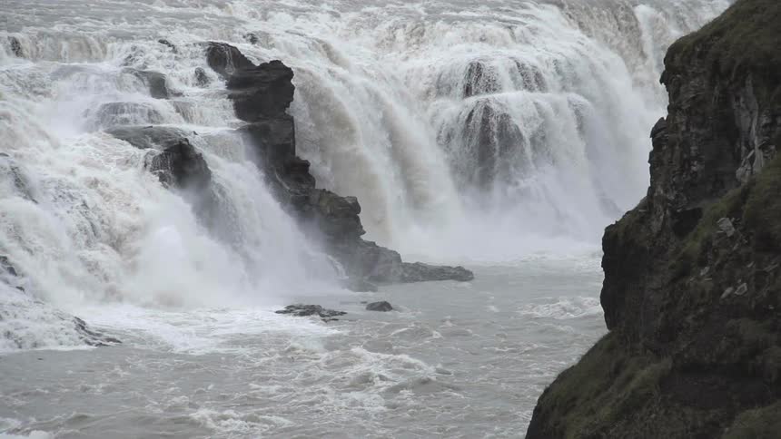 Mist rises from cascading waterfalls pouring into a river