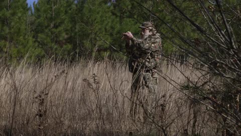 A person in camo staying in the grass