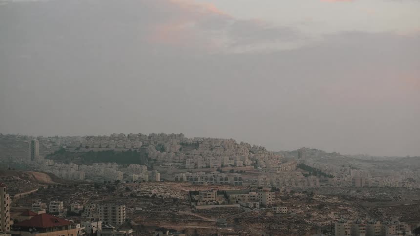 Clouds move past a city as the sun rises