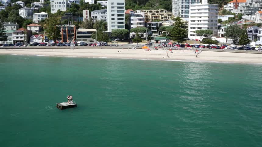 People on a beach located next to a busy road and buildings