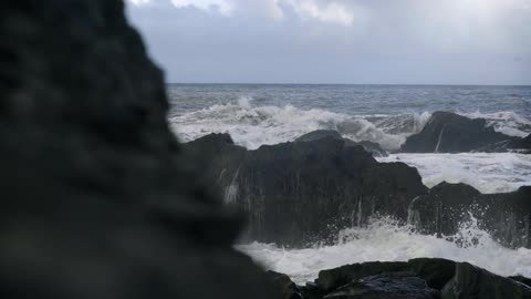 Waves crashing against rocks on an overcast day