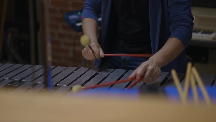 A man playing a large xylophone with a keyboard in the background
