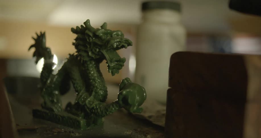 A small green statue of a dragon on a table