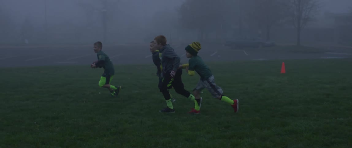 A boy is playing football with friends