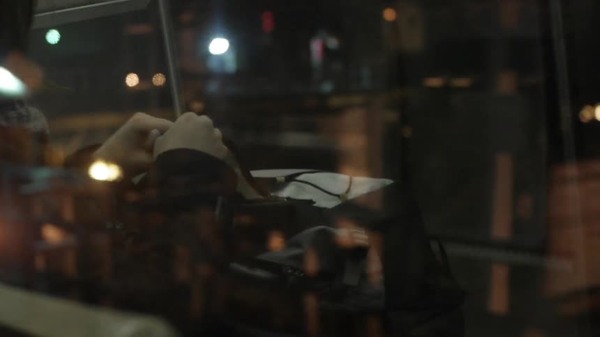 A person puts things into a bag in their lap on a bus