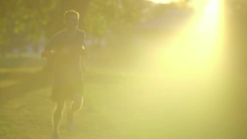 A man runs through a sunny park