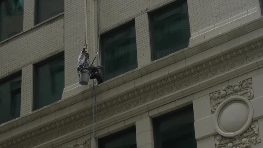 A window washer repels to the next window