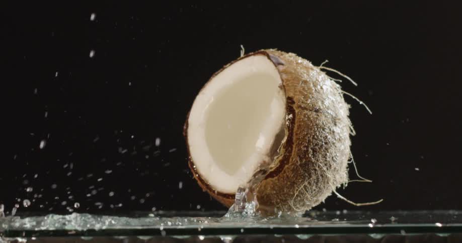 Coconut dropping on a glass table and water splashing out