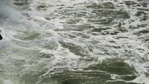 Waves crashing and foaming along the rocks of a shoreline