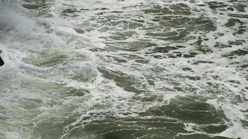 Waves crashing and foaming along the rocks of a shoreline