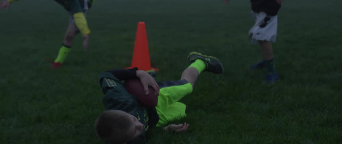 A group of boys playing football in a field in the dark