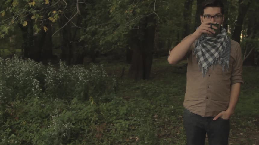 A man is drinking coffee in a field