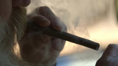 A man smokes a cigar and puffs out smoke