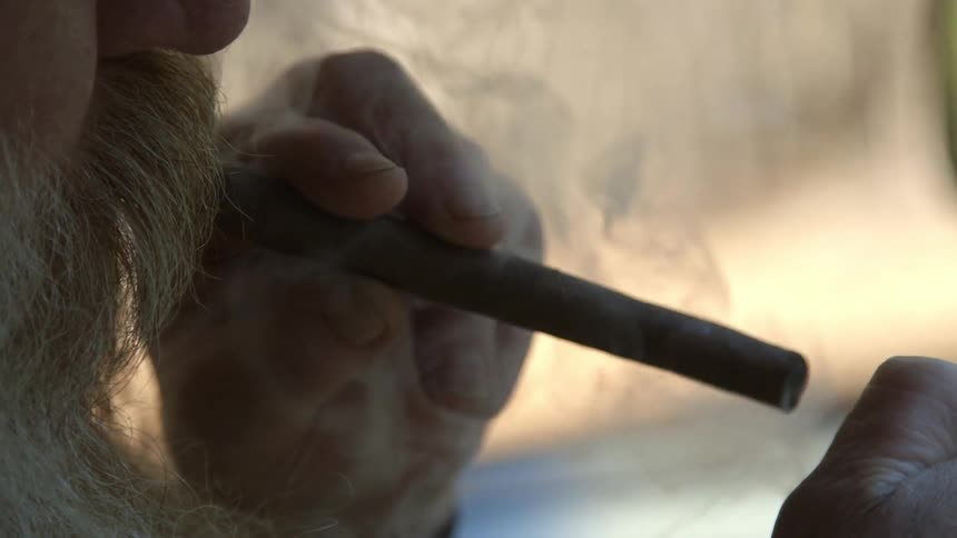 A man smokes a cigar and puffs out smoke
