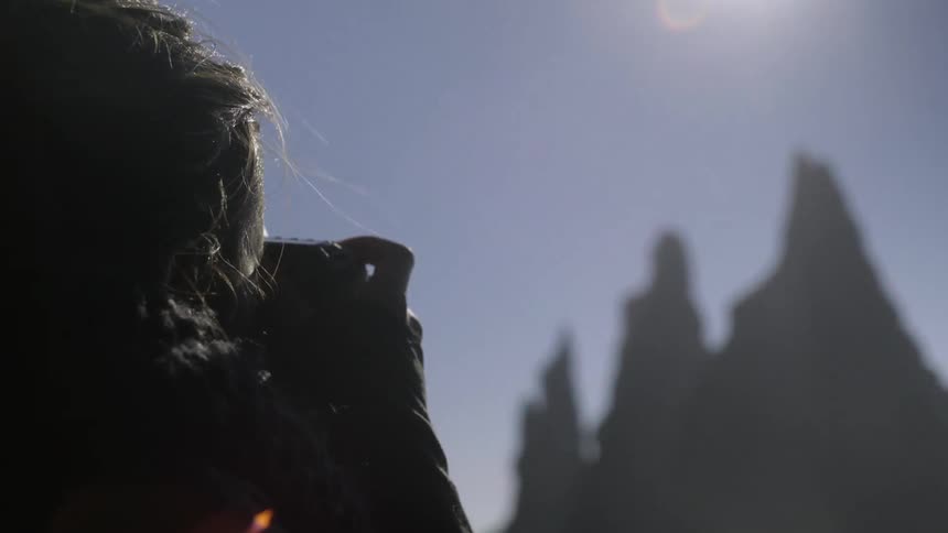 Woman taking a picture of landscape on a sunny day