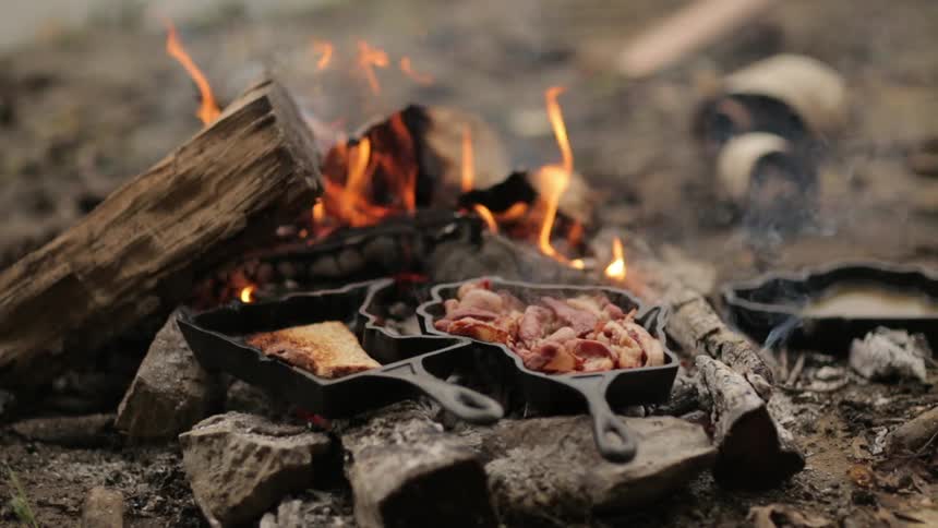 Bacon and toast cooking on a campfire