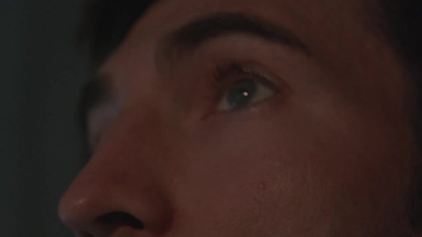 An unshaven, brunette man looking up at something