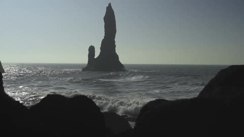 A tall rock formation protrudes from the ocean