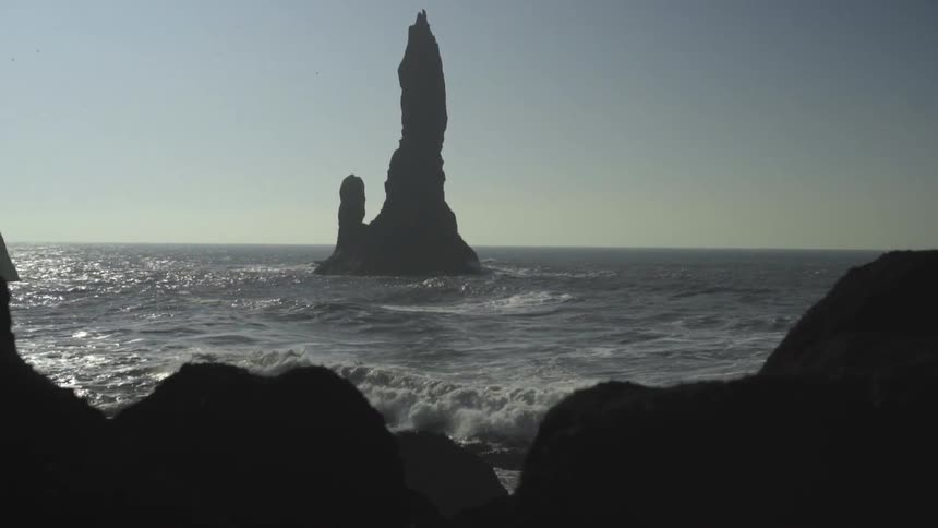 A tall rock formation protrudes from the ocean