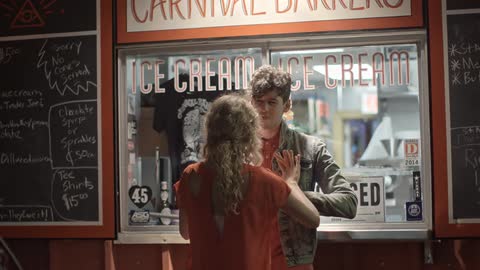 A man and a woman interact playfully outside an ice cream shoppe