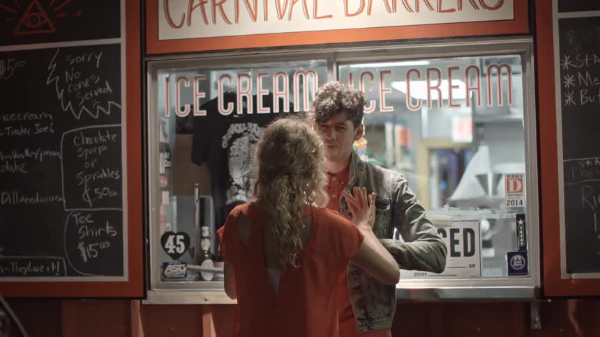 A man and a woman interact playfully outside an ice cream shoppe
