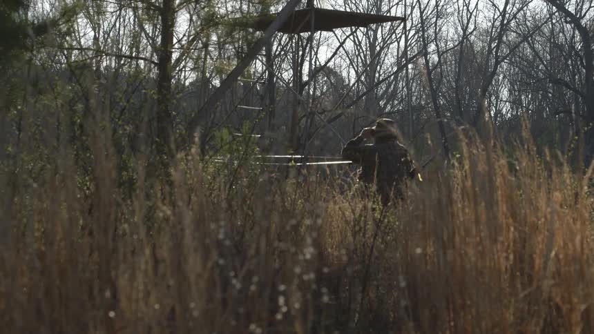 A person leaning against a rail in the middle of a field during the winter