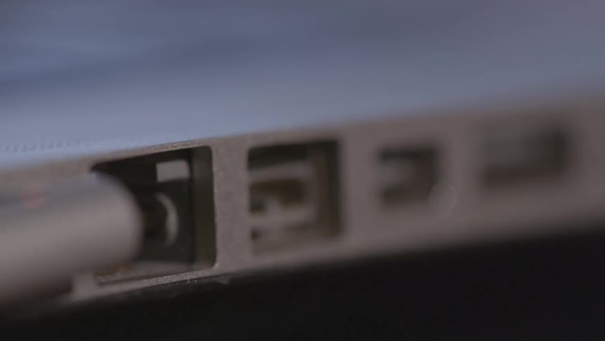 A man plugs a cord into his laptop