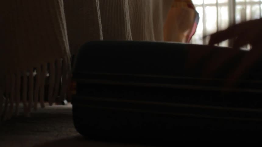 A woman removes her luggage from her bed