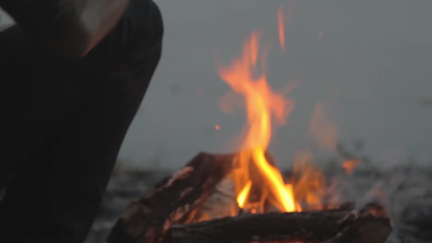 A campfire burns and smokes