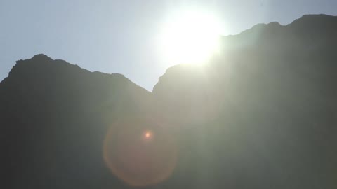 Silhouetted view of rocky hills with the sun in the background